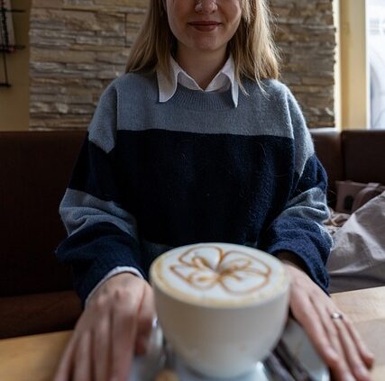 Primo piano di una ragazza sorridente con una tazza di cappuccino decorata